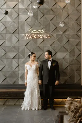 Novios posando frente a muro geométrico con letrero neón Oaxaca Mi Amor coordinado por Wedding Planner Oaxaca.