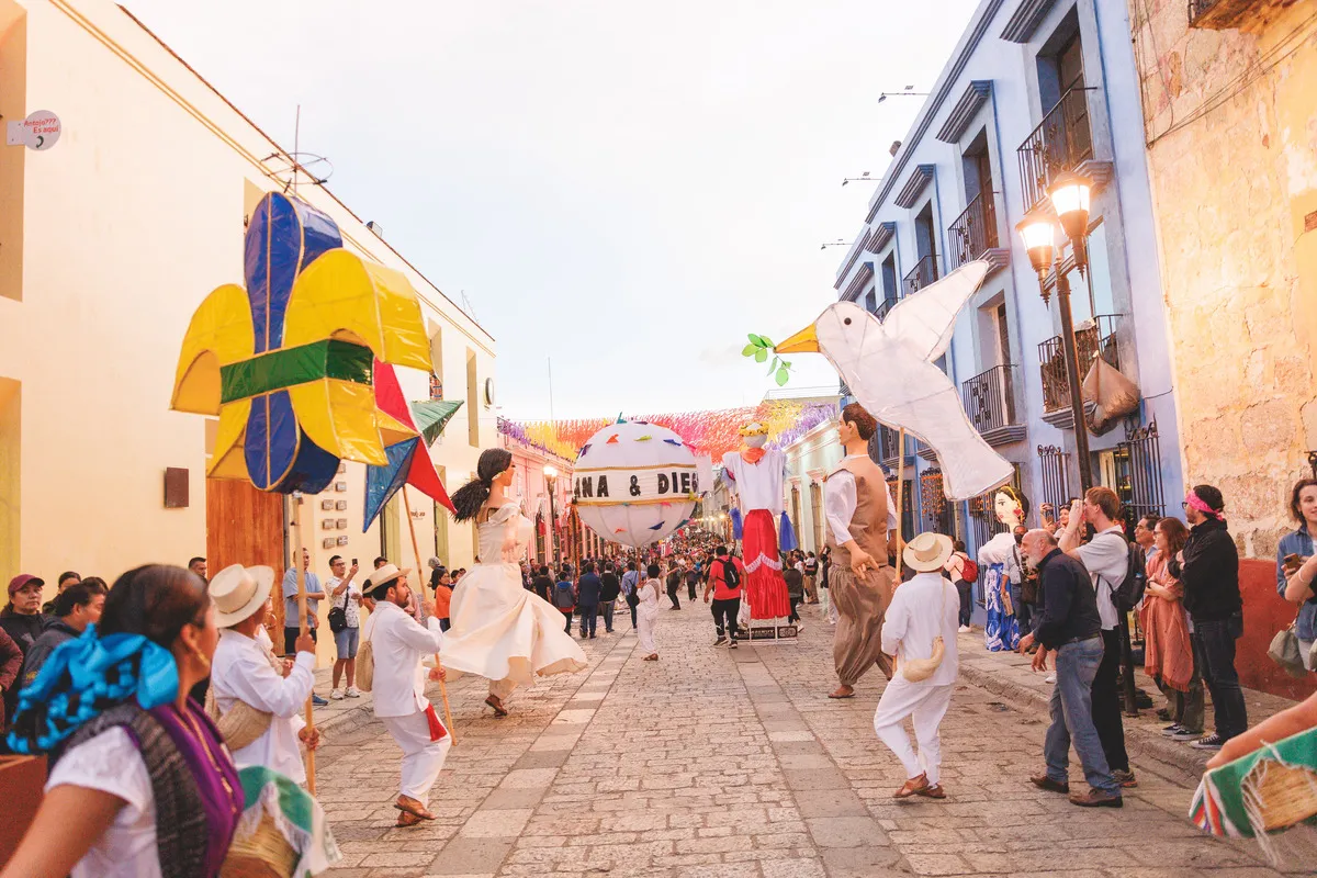 Novios celebrando en una calenda tradicional con moños de calenda gigantes, coordinada por una wedding planner local.