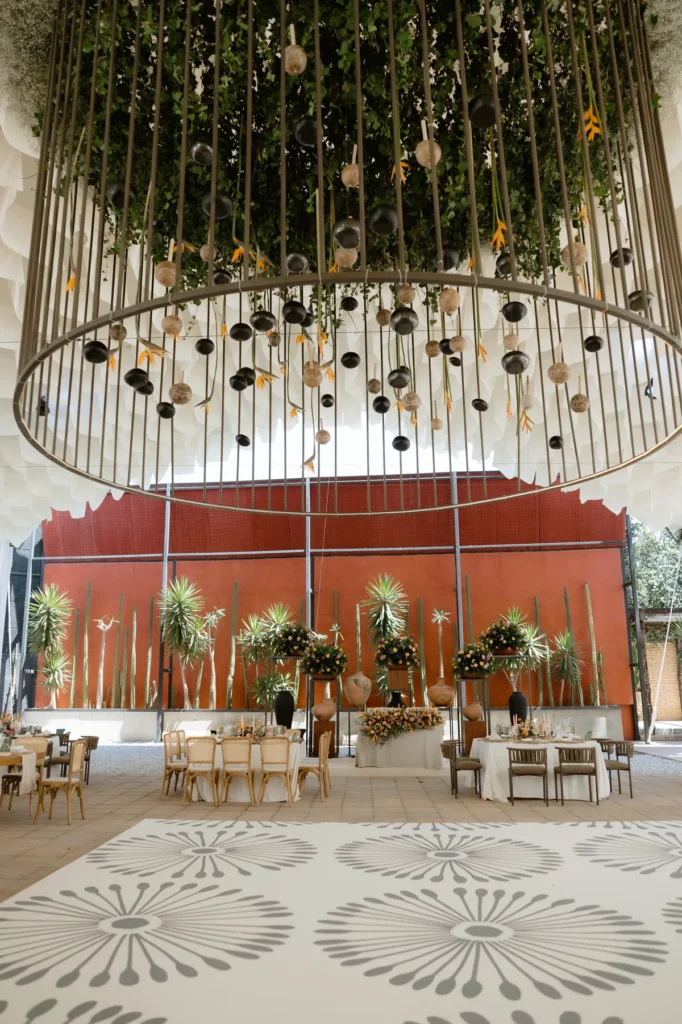 Montaje de banquete de boda con estructura circular colgante de follaje y flores diseñado por una wedding planner experta.