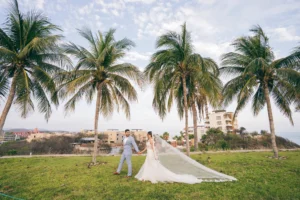 Cómo organizar una boda: Fotografía de una pareja de recién casados caminando por el pasto tomados de la mano.