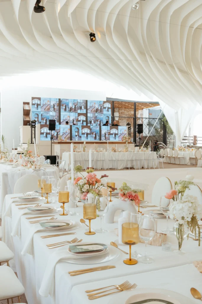 Salón de eventos con techo de tela ondulada y pantallas LED, una propuesta de lujo para bodas en la playa modernas.